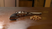 Handgun on a table next to a pile of peanuts